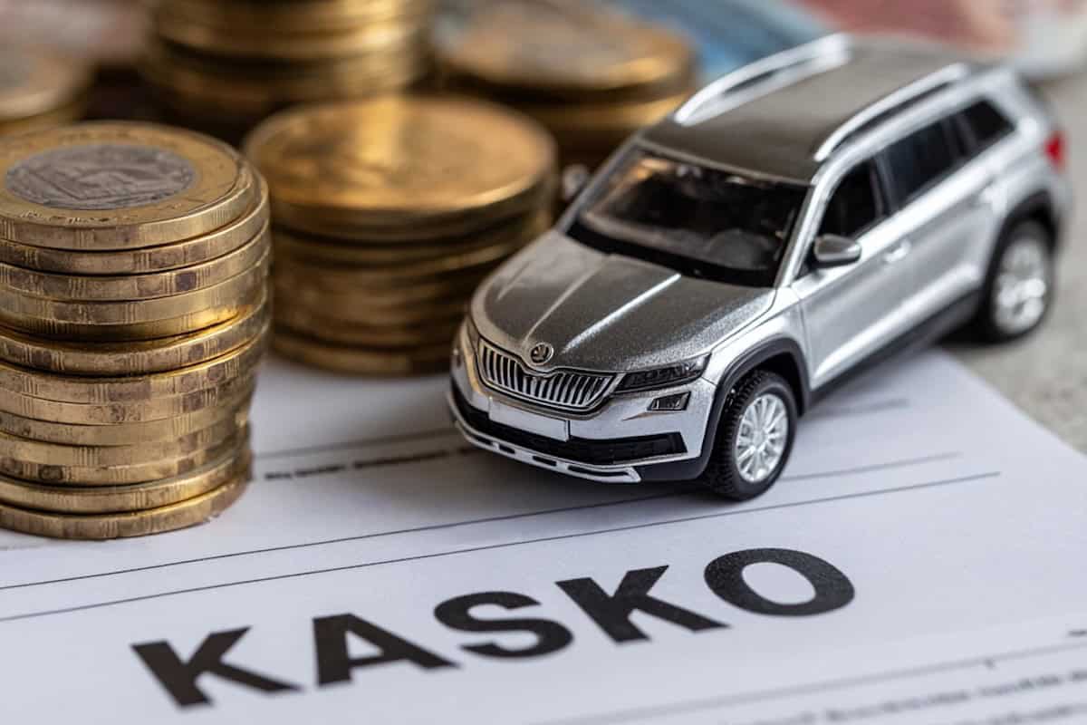 Modellino di auto SUV su un documento assicurativo con la scritta Kasko e monete impilate, a rappresentare i costi e la copertura dell’assicurazione auto Kasko.