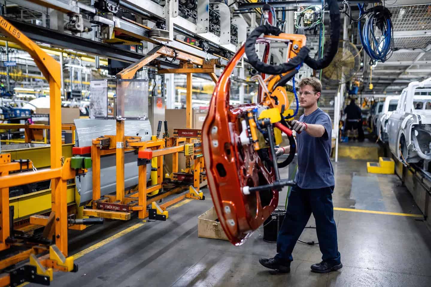 Operaio in fabbrica Ford a assemblare parti di automobili in linea di produzione.