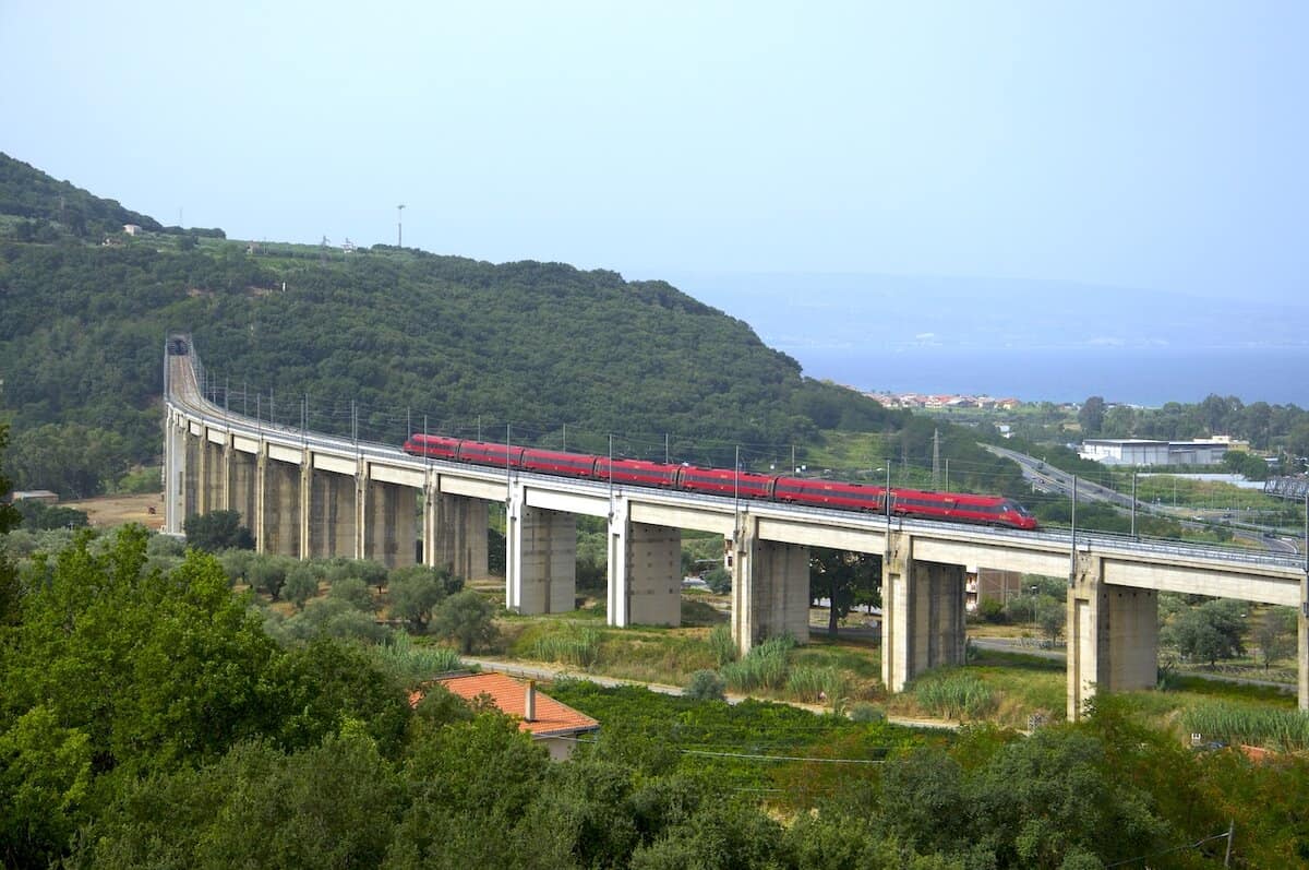 Treno Italo rosso ETR 675 EVO alta velocità su viadotto in Italia, paesaggio collinare, vista laterale.