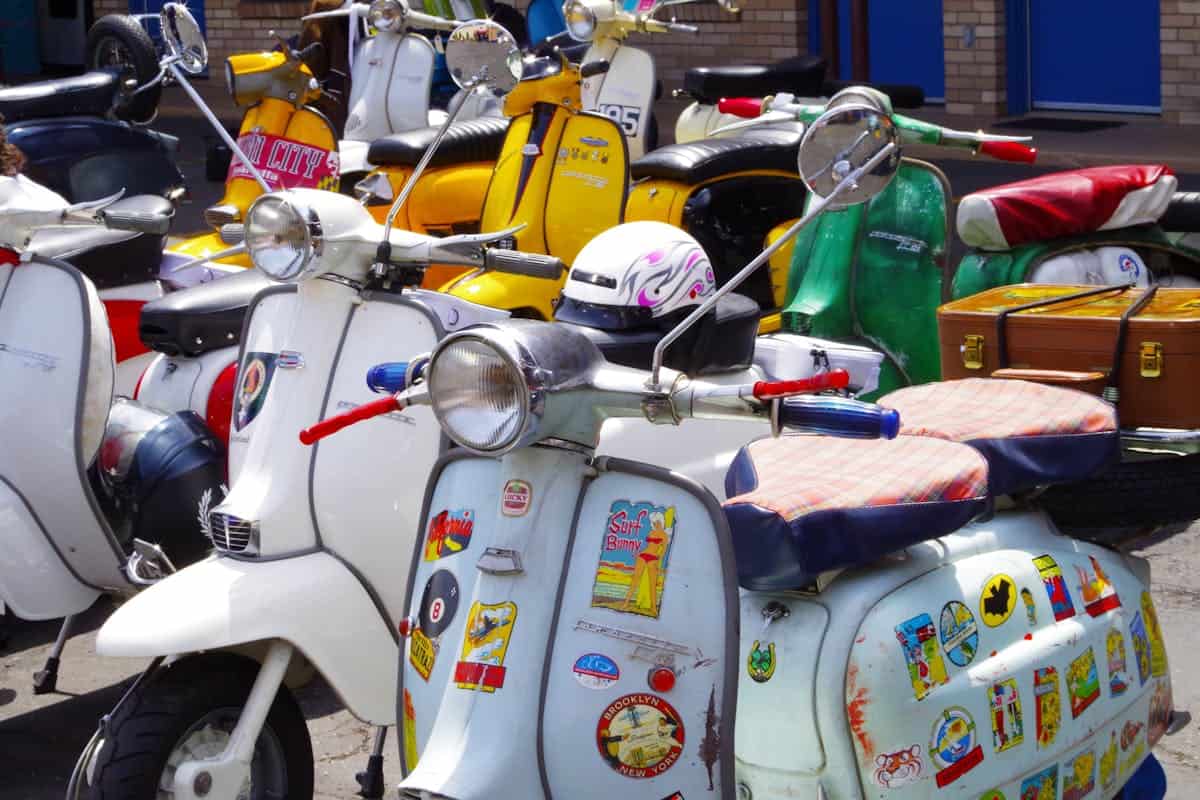 Alt: Vespa d'epoca con adesivi colorati e bagagliaio vintage, perfetta per collezionisti e appassionati di motori storici, in mostra a un raduno motociclistico.