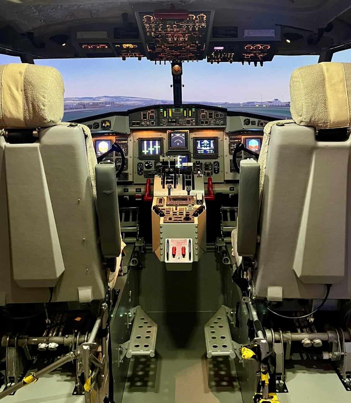 Cabina di pilotaggio di aereo simulatore di volo Canadair a Malpensa con display digitali e comandi moderni.