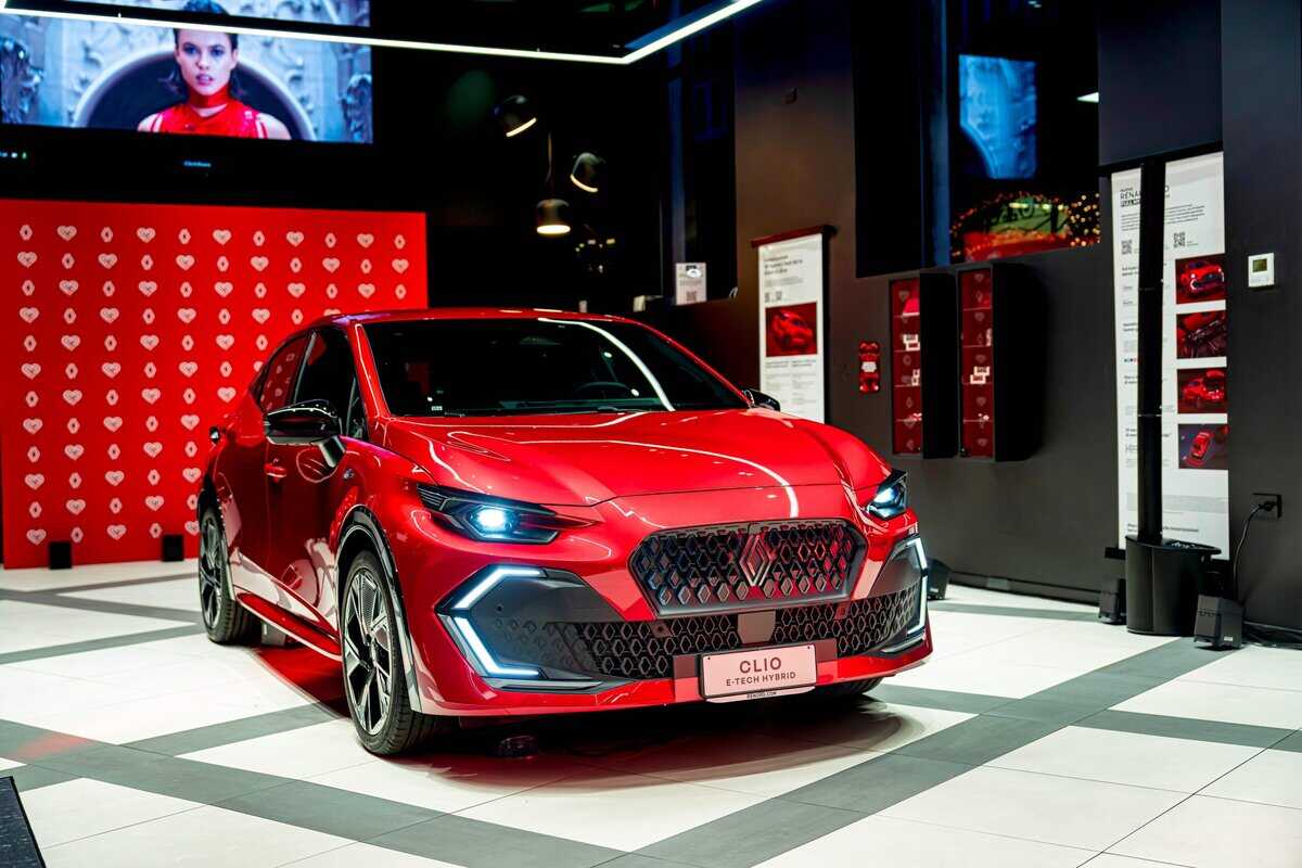 Renault Clio E-Tech Hybrid rossa Cliorama in esposizione frontale in showroom illuminato