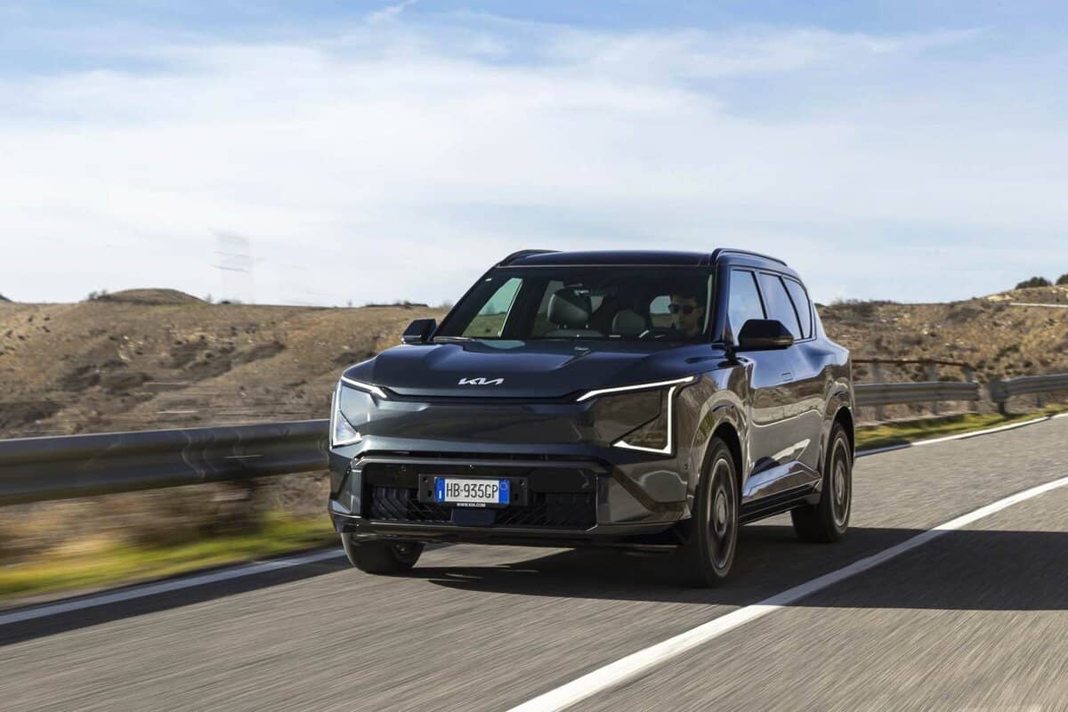 Kia EV5 nera su strada, ripresa frontale, paesaggio arido, giorno.