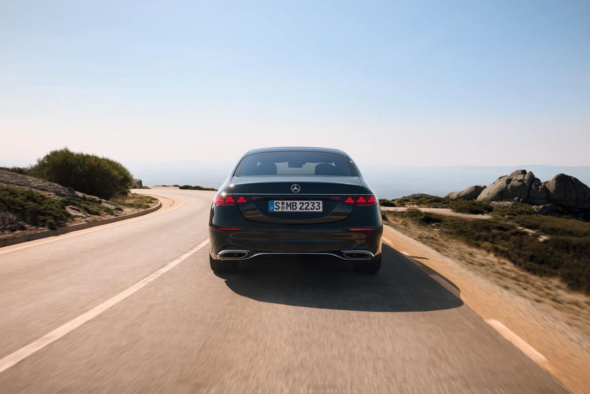 Mercedes-Benz Classe S nera vista posteriore su strada tortuosa, paesaggio roccioso, cielo sereno.