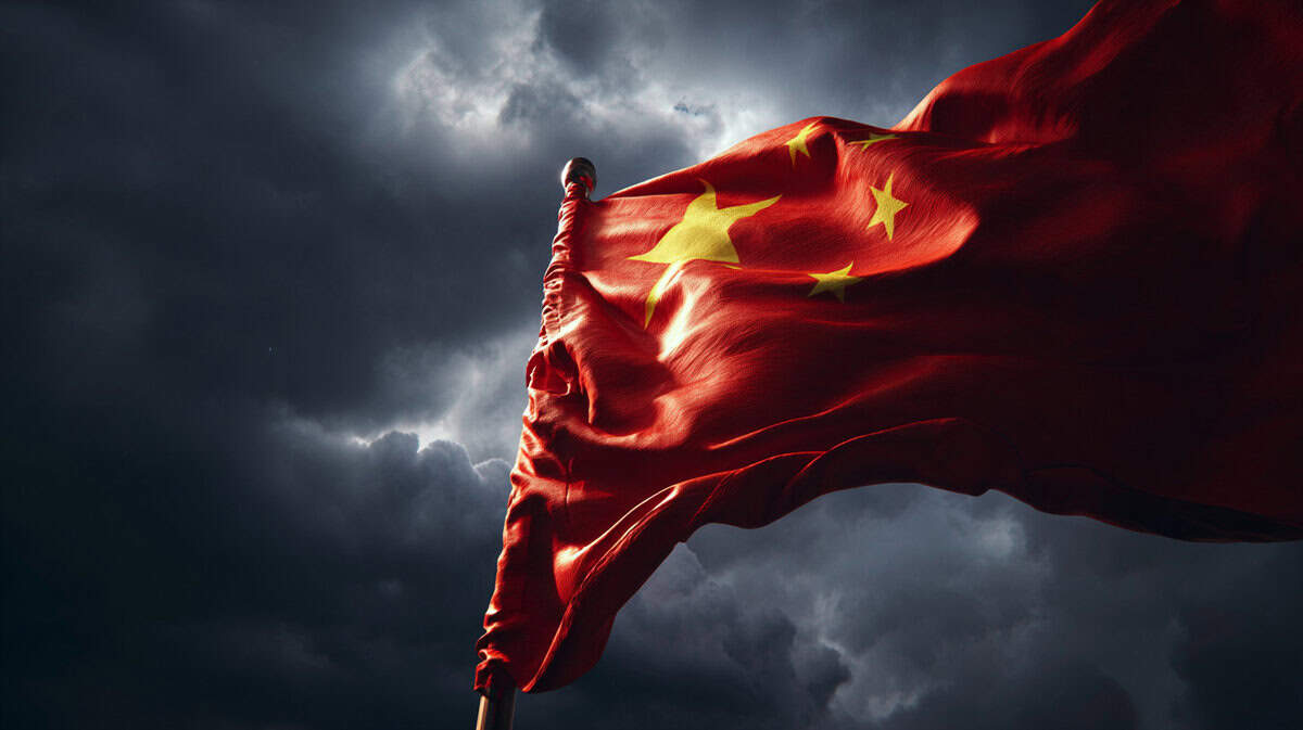 Bandiera della Cina ondeggia contro un cielo nuvoloso carico, vista angolata dal basso, tensione atmosferica.