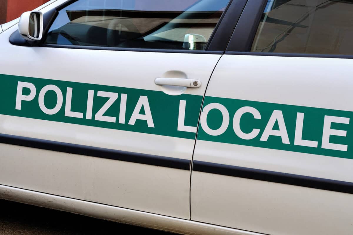Auto bianca Polizia Locale con scritta verde, dettaglio portiera, vista laterale, contesto urbano.