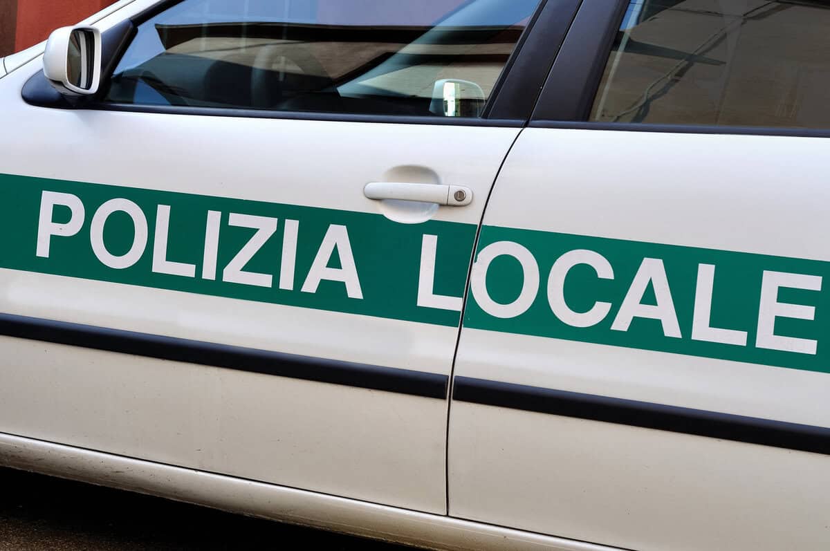 Auto bianca Polizia Locale con scritta verde, dettaglio portiera, vista laterale, contesto urbano.