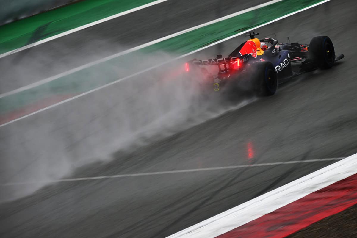 Red Bull F1, corsa bagnata, pista asfaltata, vista posteriore, in velocità su circuito.