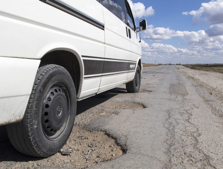 Ruota di un furgone su strada sterrata danneggiata in campagna.