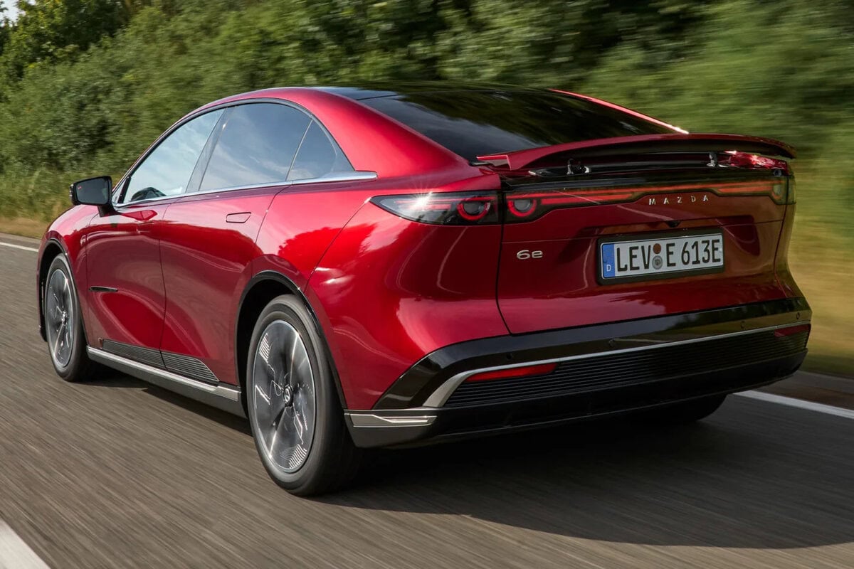 Retro della Mazda 6e 2025 EV su strada, con fanali posteriori sottili e spoiler integrato.