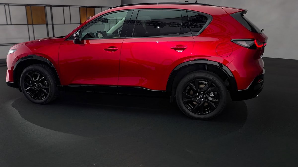 Vista laterale della Mazda CX-5 AWD 2025 in livrea Soul Red Crystal con cerchi neri