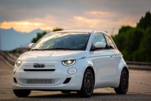 The white fiat 500 is parked on the road.