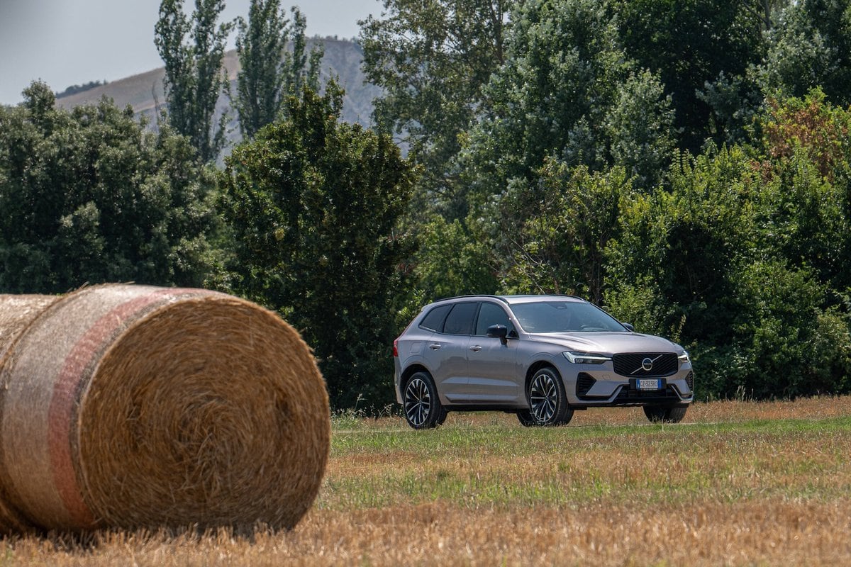 Volvo XC60 Plug-in Hybrid 2025 parcheggiata in un campo con rotolo di fieno