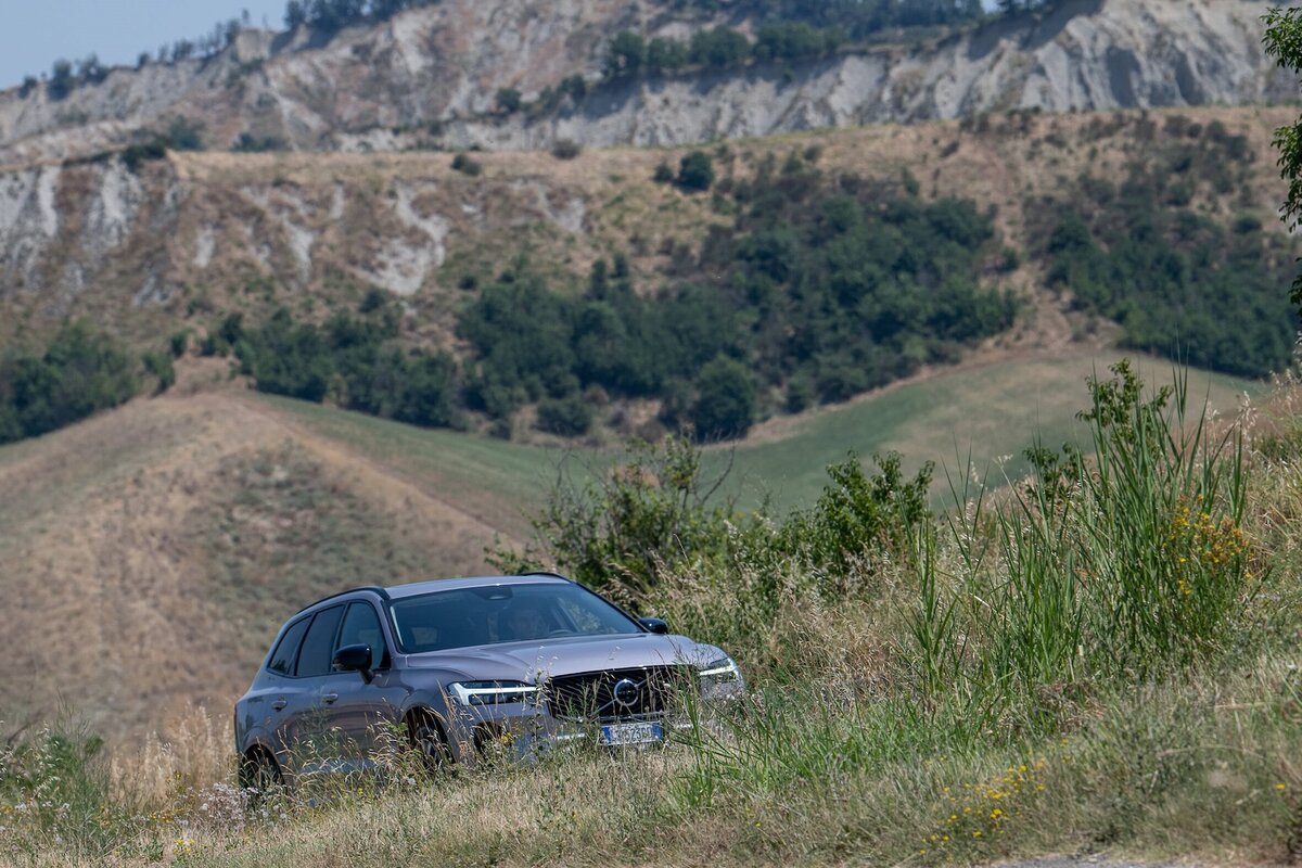 Volvo XC60 Plug-in Hybrid 2025 in fuoristrada leggero con colline sullo sfondo
