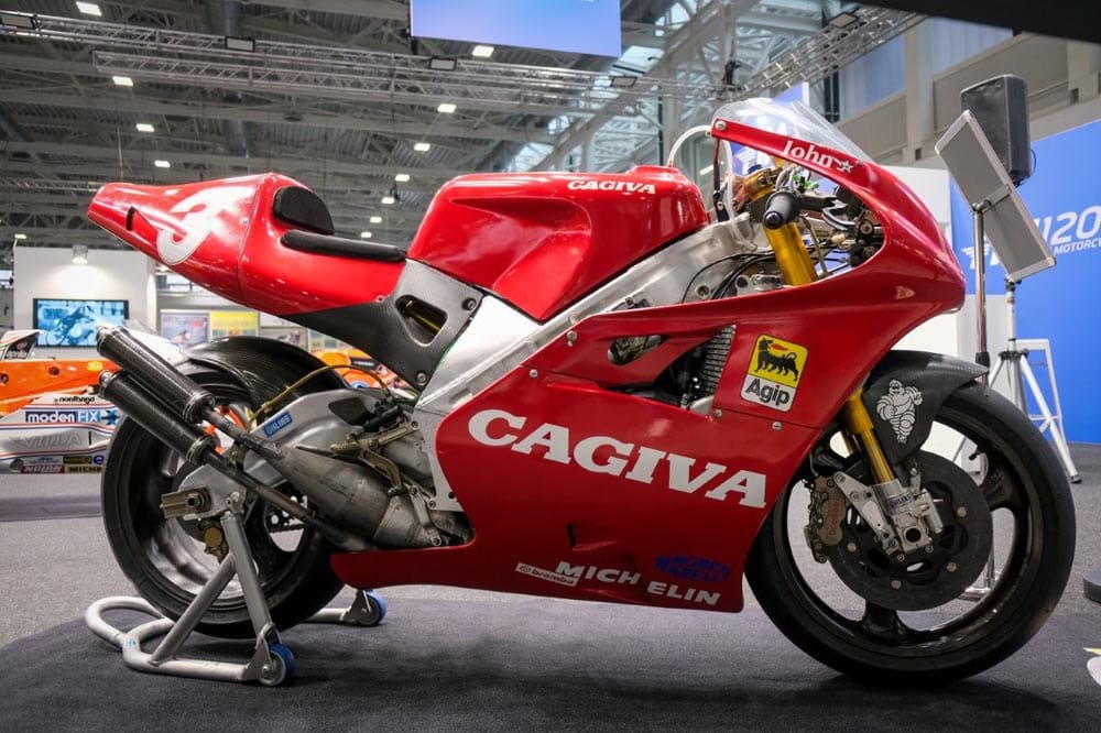 Cagiva C594 da gara, carenata rossa numero 3 con livrea Agip e Michelin, fotografata lateralmente a una mostra a Bologna.