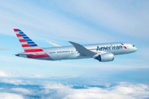 Boeing 787 di American Airlines American Airlines in volo sopra le nuvole, con livrea grigia e coda a strisce rosse e blu.