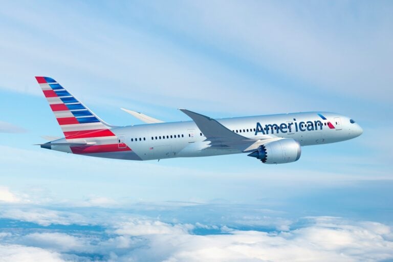 Boeing 787 di American Airlines American Airlines in volo sopra le nuvole, con livrea grigia e coda a strisce rosse e blu.