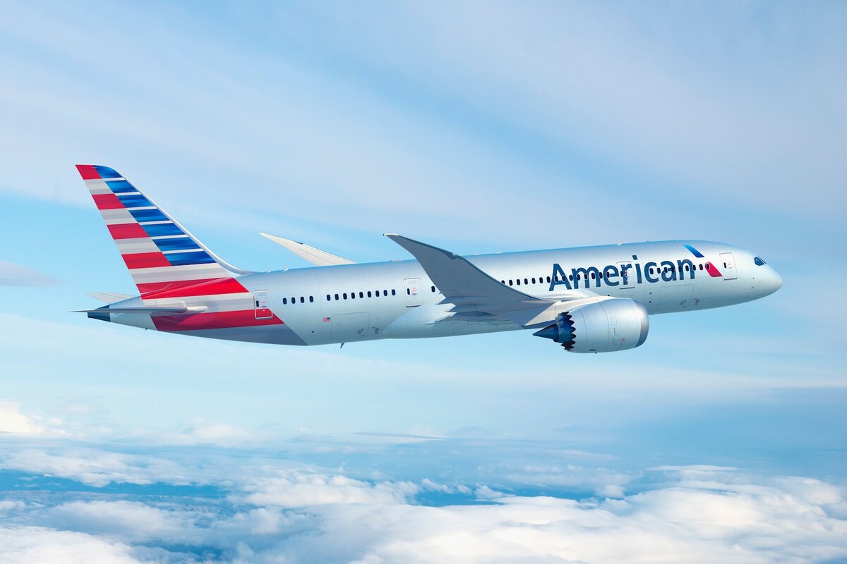 Boeing 787 di American Airlines American Airlines in volo sopra le nuvole, con livrea grigia e coda a strisce rosse e blu.