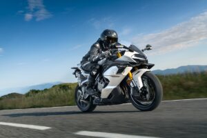 Motociclista in tuta nera guida la CFMoto 750SR-S bianca su strada di montagna.