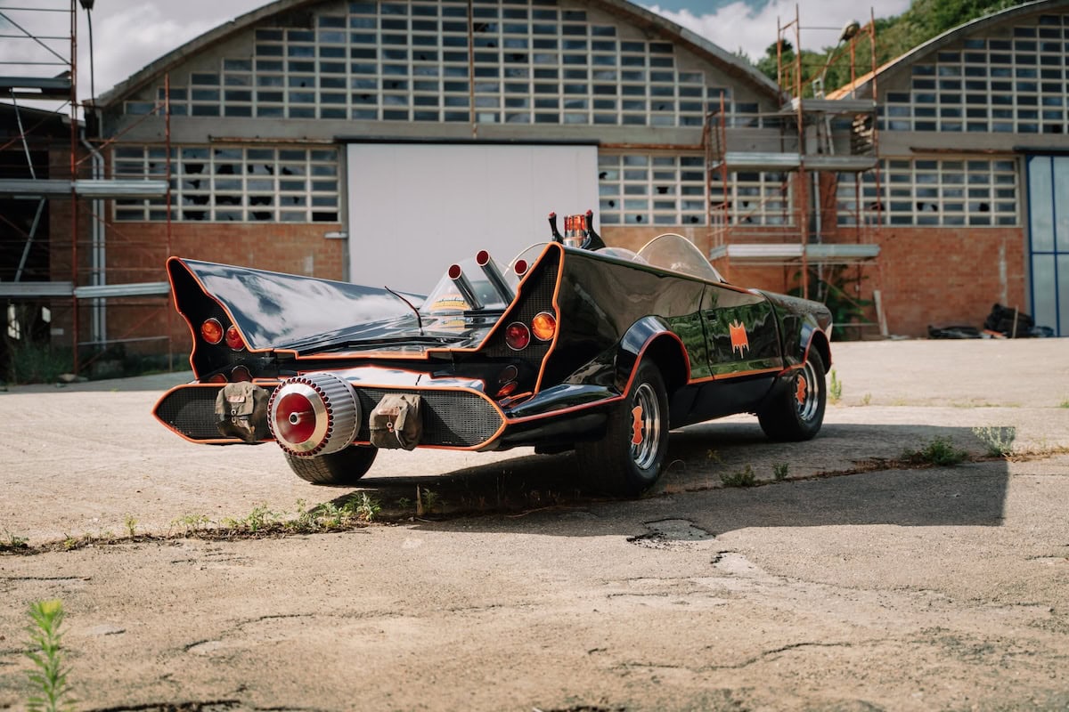 Retro della Batmobile con propulsore a turbina e dettagli rossi, fotografata in un'area urbana dismessa.