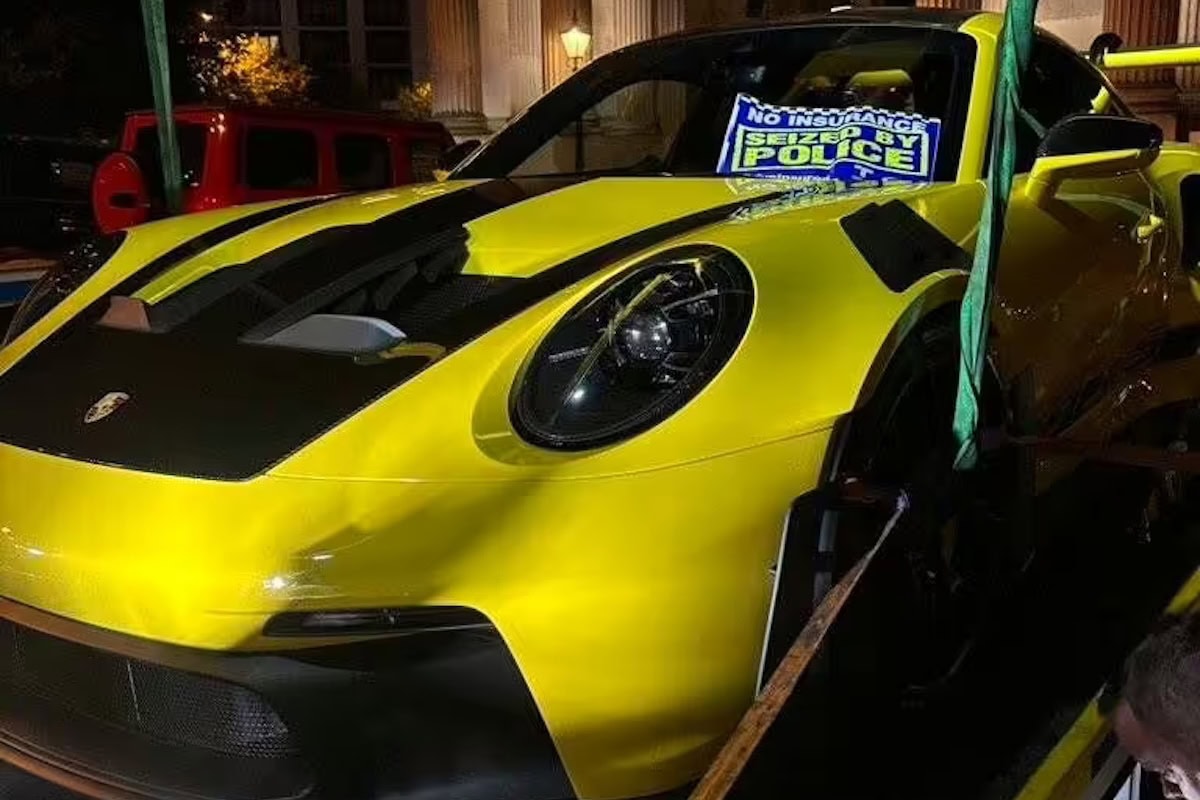 Porsche gialla su carro attrezzi con cartello “Seized by Police” per assenza di assicurazione.
