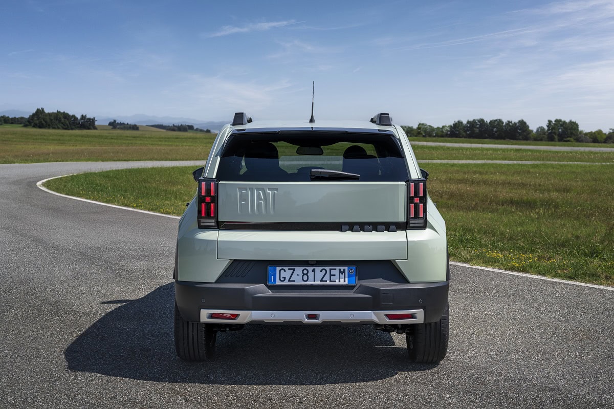 Fiat Grande Panda vista da dietro in un ambiente naturale con strade lastricate e paesaggi verdi, perfetta per gli amanti delle auto compatte e sostenibili.