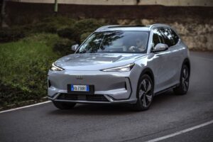 Auto elettrica Geely EX5 in movimento su strada, design futuristico e sostenibile, tecnologia avanzata, veicolo ecologico, innovazione automobilistica.