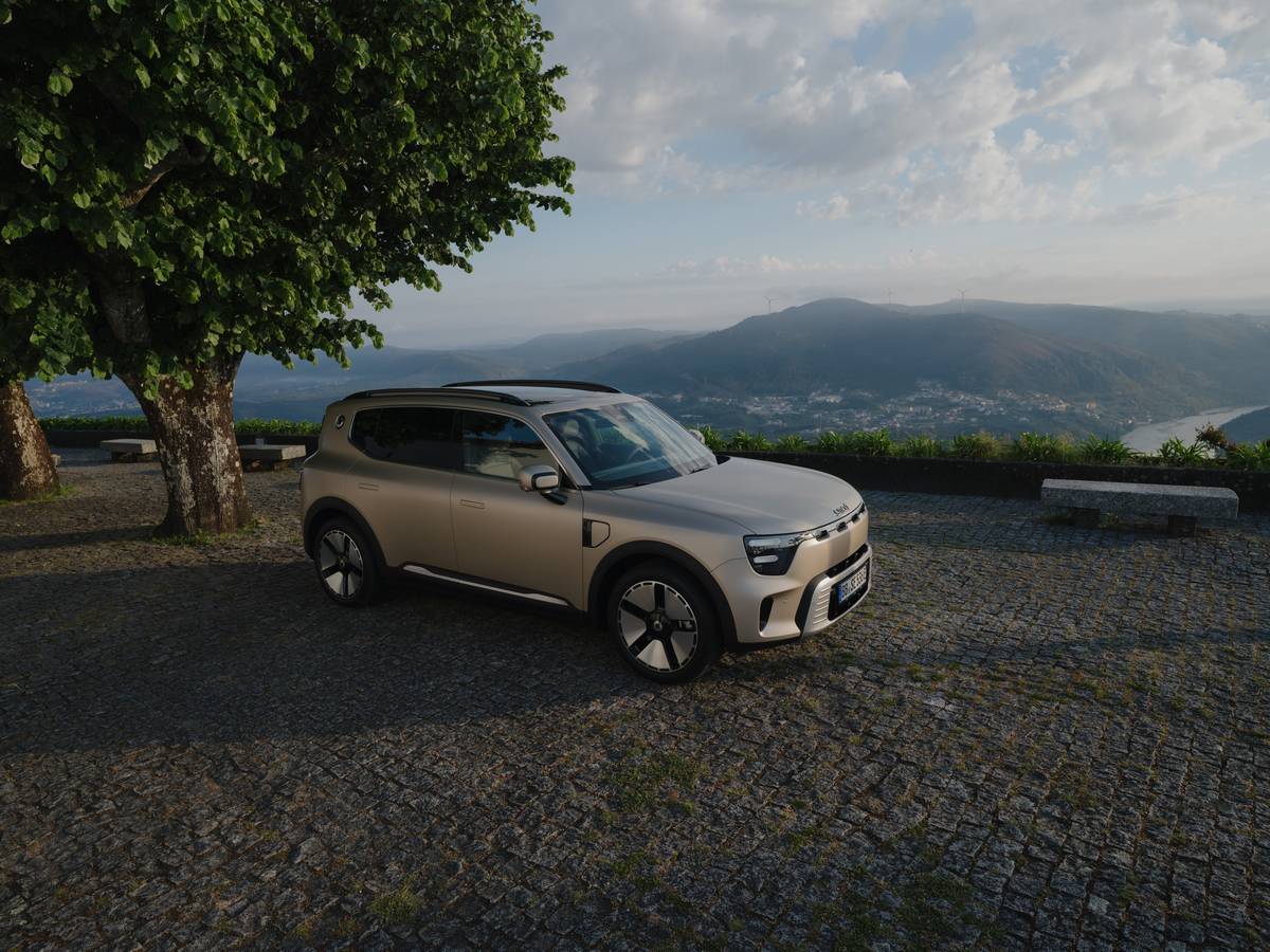 Auto elettrica SUV su strada panoramica con paesaggio montano e cielo nuvoloso.