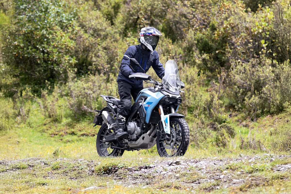Un motociclista guida la Morbidelli T502X azzurra su un sentiero erboso tra vegetazione rigogliosa, pronto per un tratto off-road.