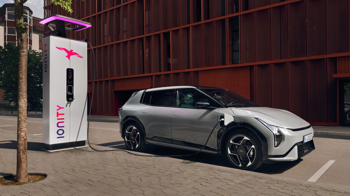 Veicolo elettrico Kia EV6 in ricarica presso punto di ricarica pubblico in città.