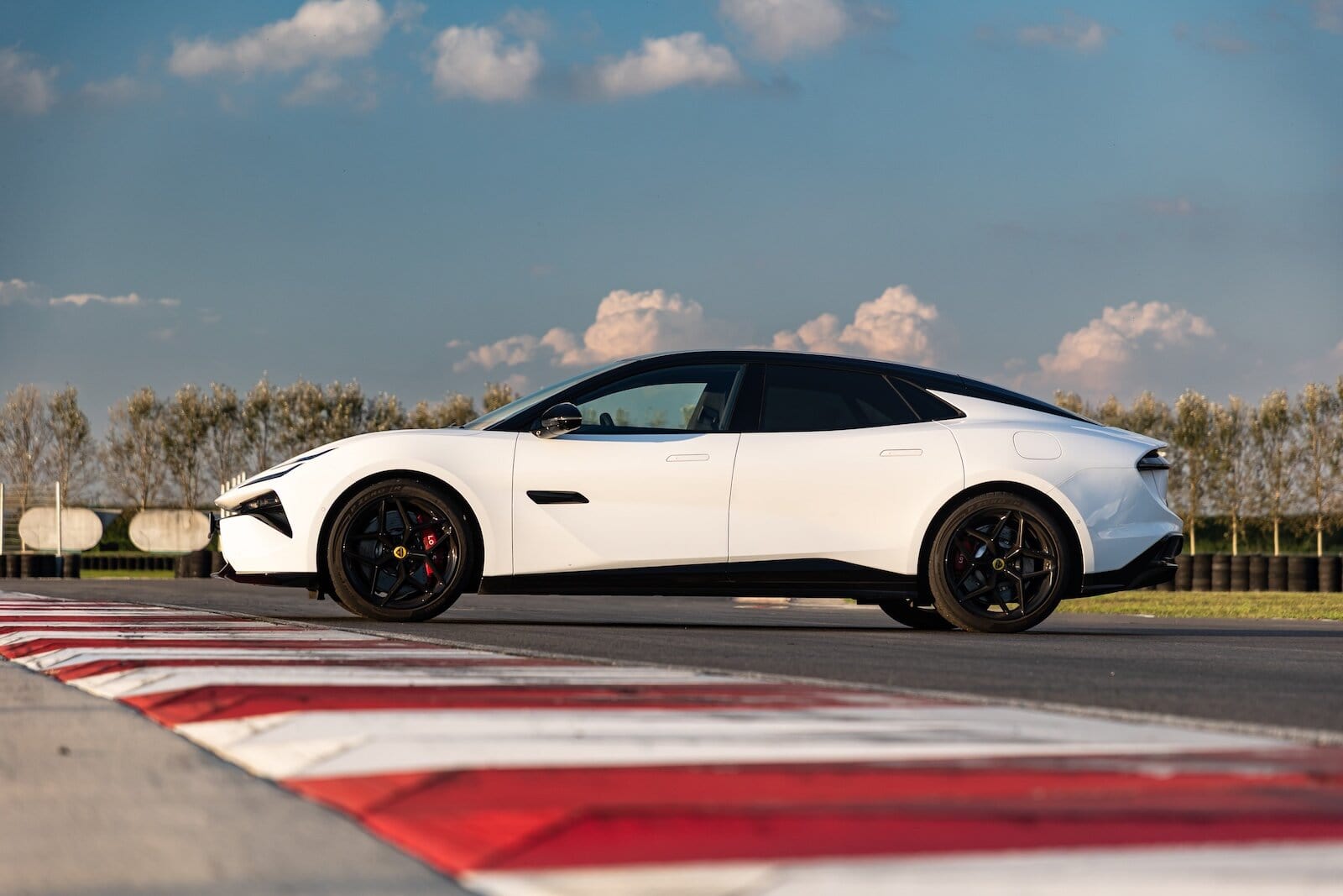 Auto sportiva elettrica Lotus Emeya 600 Sport SE su pista da corsa, carrozzeria bianca e dettagli in nero, design aerodinamico con pneumatici ad alte prestazioni.
