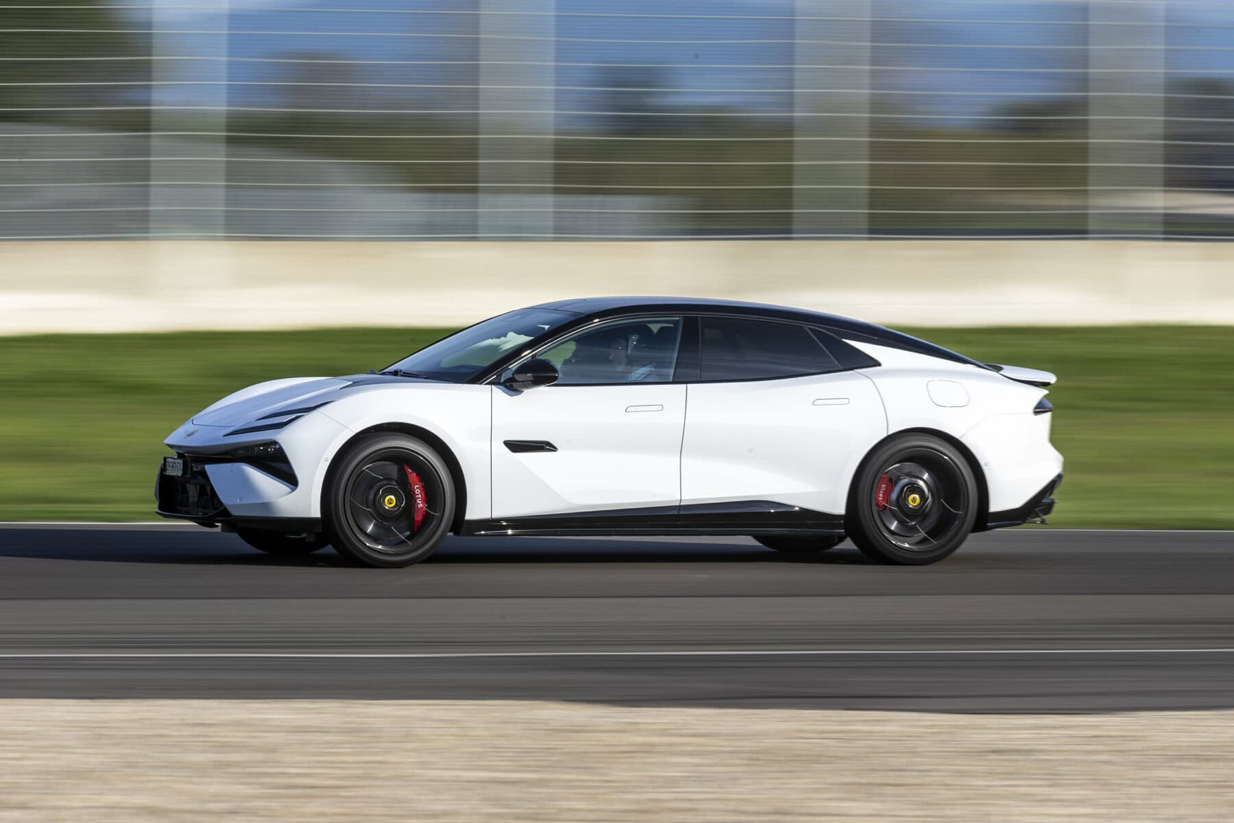 Auto sportiva Lotus Emeya 600 Sport SE con design aerodinamico, veicolo elettrico ad alte prestazioni, dettagli di stile moderno, pneumatici sportivi e freni rossi, velocità su strada.