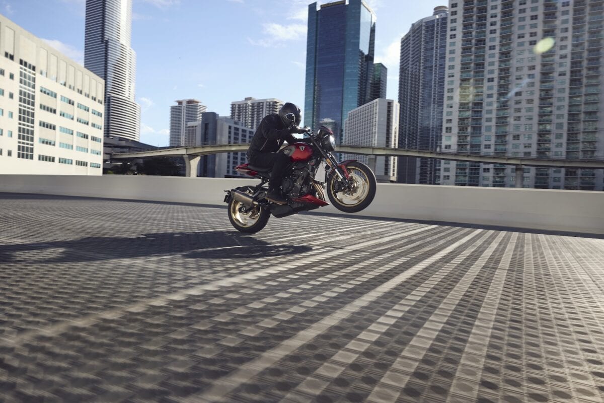 Moto sportiva in avatar di un motociclista che esegue una manovra acrobatica in un contesto urbano moderno con grattacieli.