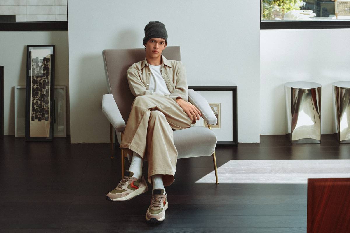 Young man sitting on modern armchair in stylish interior, casual fashion and relaxed atmosphere, minimalistic decor with contemporary art and furniture, cozy home living space.