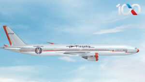 Boeing 747 in livrea commemorativa 100 anni American Airlines in volo con cielo blu sullo sfondo.