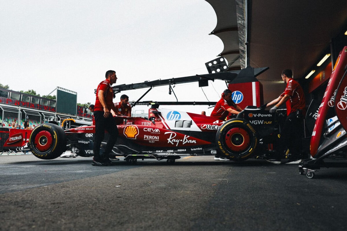 Ferrari Formula 1 2025 in stazione di pit stop con team che lavora nel box.