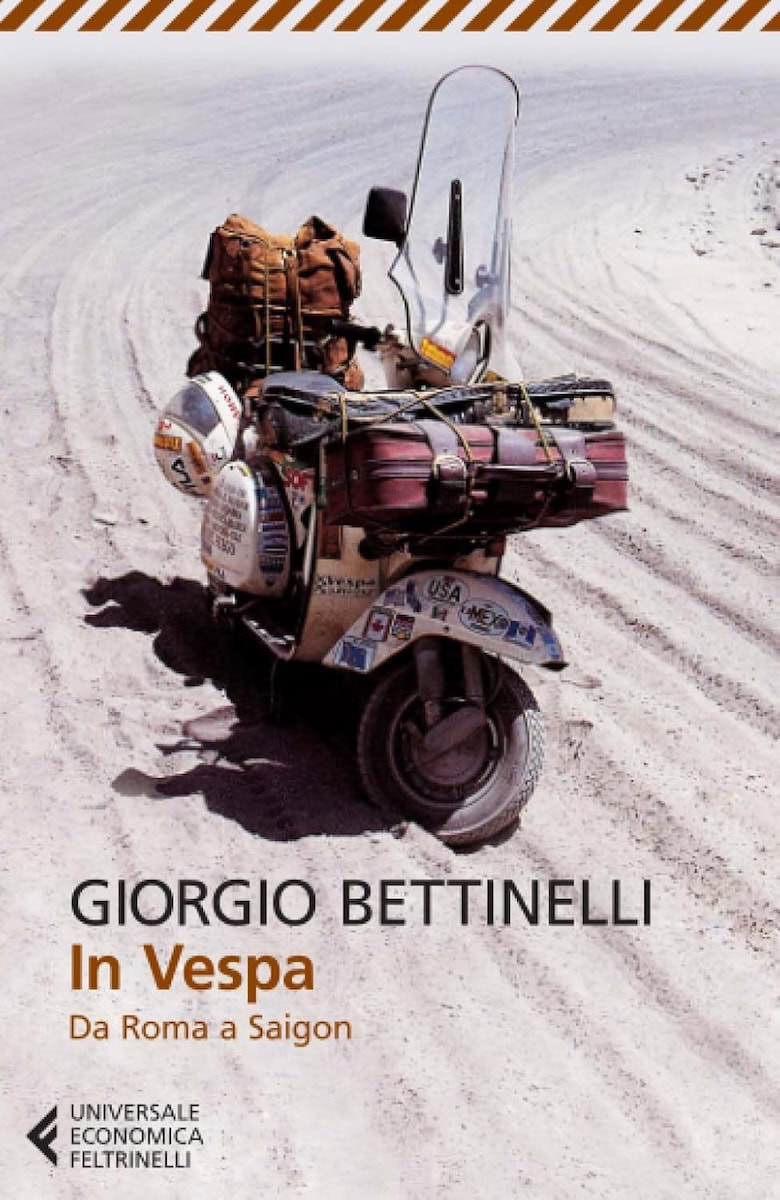 Scooter Vespa Piaggio con bagagli in un paesaggio desertico, viaggio avventuroso e nomade, esplorazione e libertà su due ruote, viaggio in Vespa dall'Italia al Sud-est asiatico.