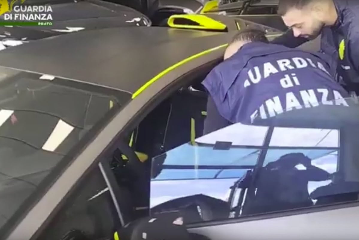 Militare della Guardia di Finanza controlla un'auto di lusso in un garage.