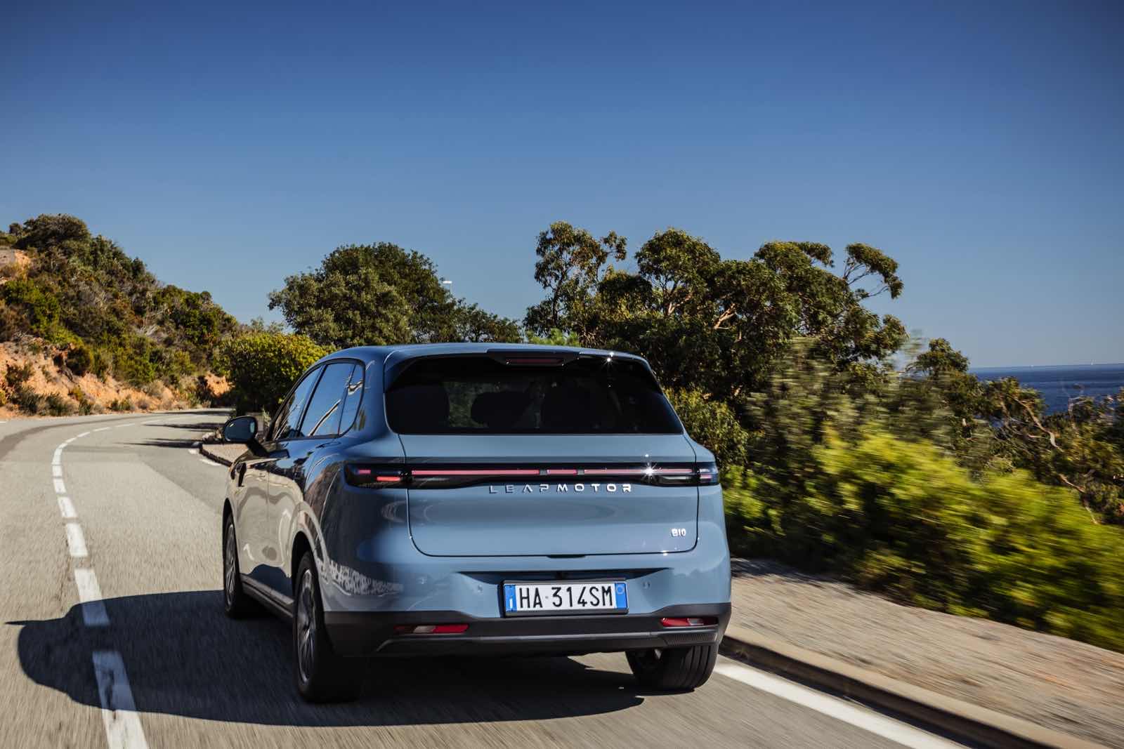 Automobile elettrica Leapmotor B10 in movimento sulla strada panoramica vicino al mare.