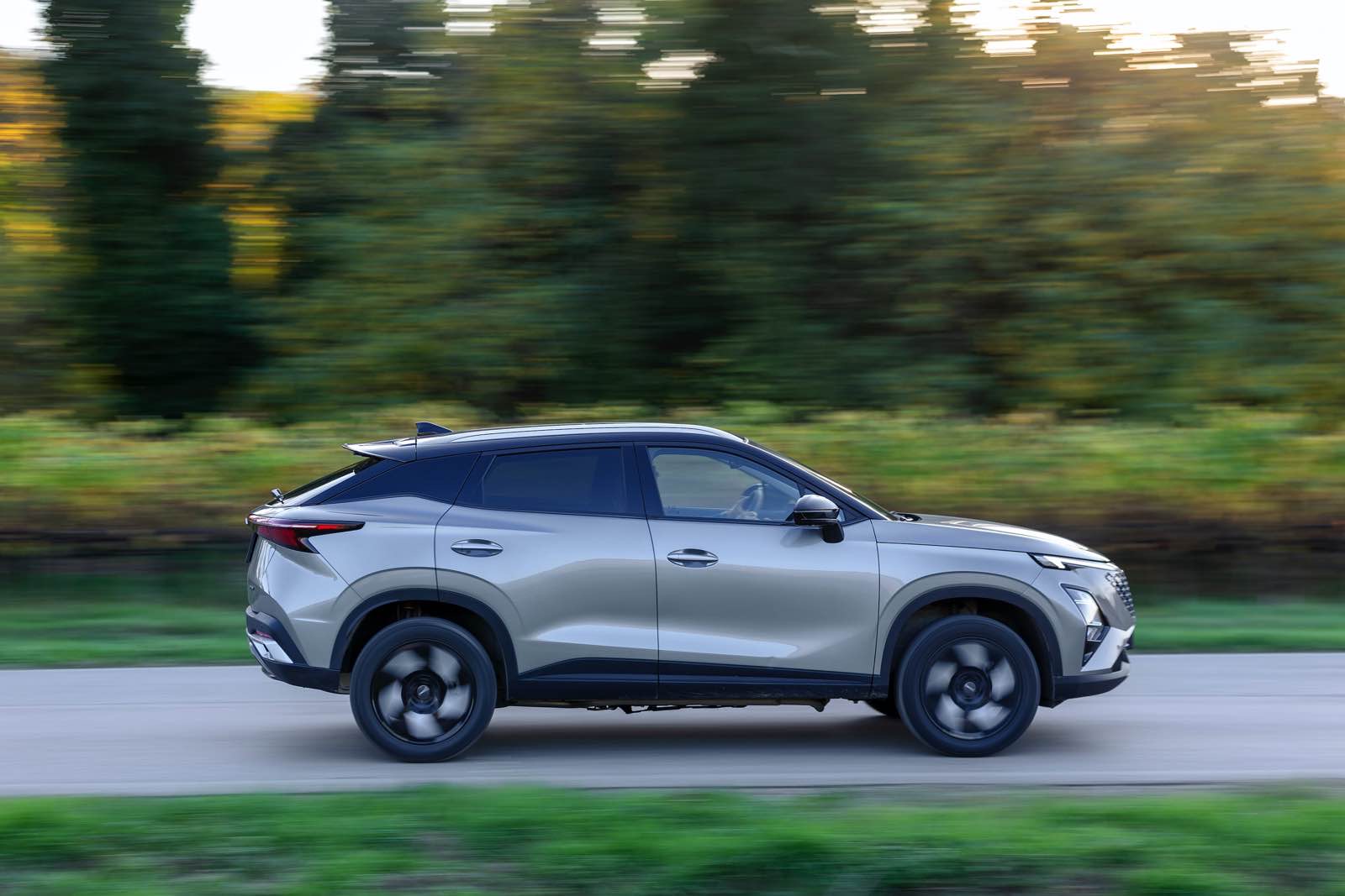 Auto SUV Omoda 5 SHS-S in movimento su strada, vista laterale.