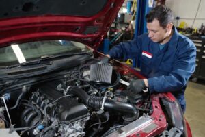 Filtro dell'aria dell'automobile, manovra di assemblaggio da parte di un meccanico in officina, manutenzione del veicolo e intervento di riparazione motore.