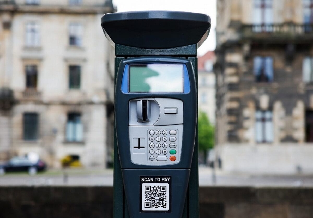 Parcometro con schermo digitale e QR code per pagamento tramite smartphone, sito per parcheggi a pagamento in città.