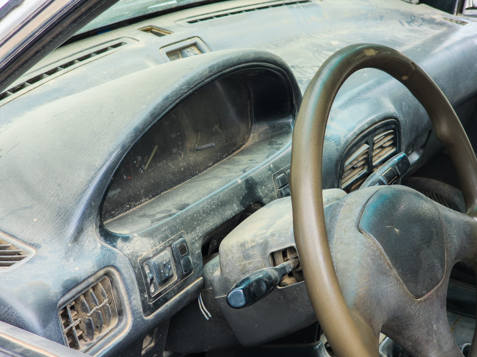 Interni auto vecchia e polverosa, cruscotto sporco e polveroso, volante usurato e abbandonato, immagine di un'auto in cattive condizioni, difficile da guidare.