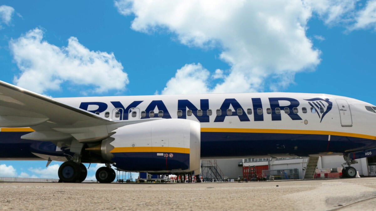 Aereo Ryanair parcheggiato in aeroporto con cielo sereno e nuvole bianche.