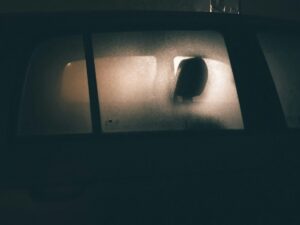 Vetro posteriore dell'auto con condensa e vista del sedile interno, foto notturna.