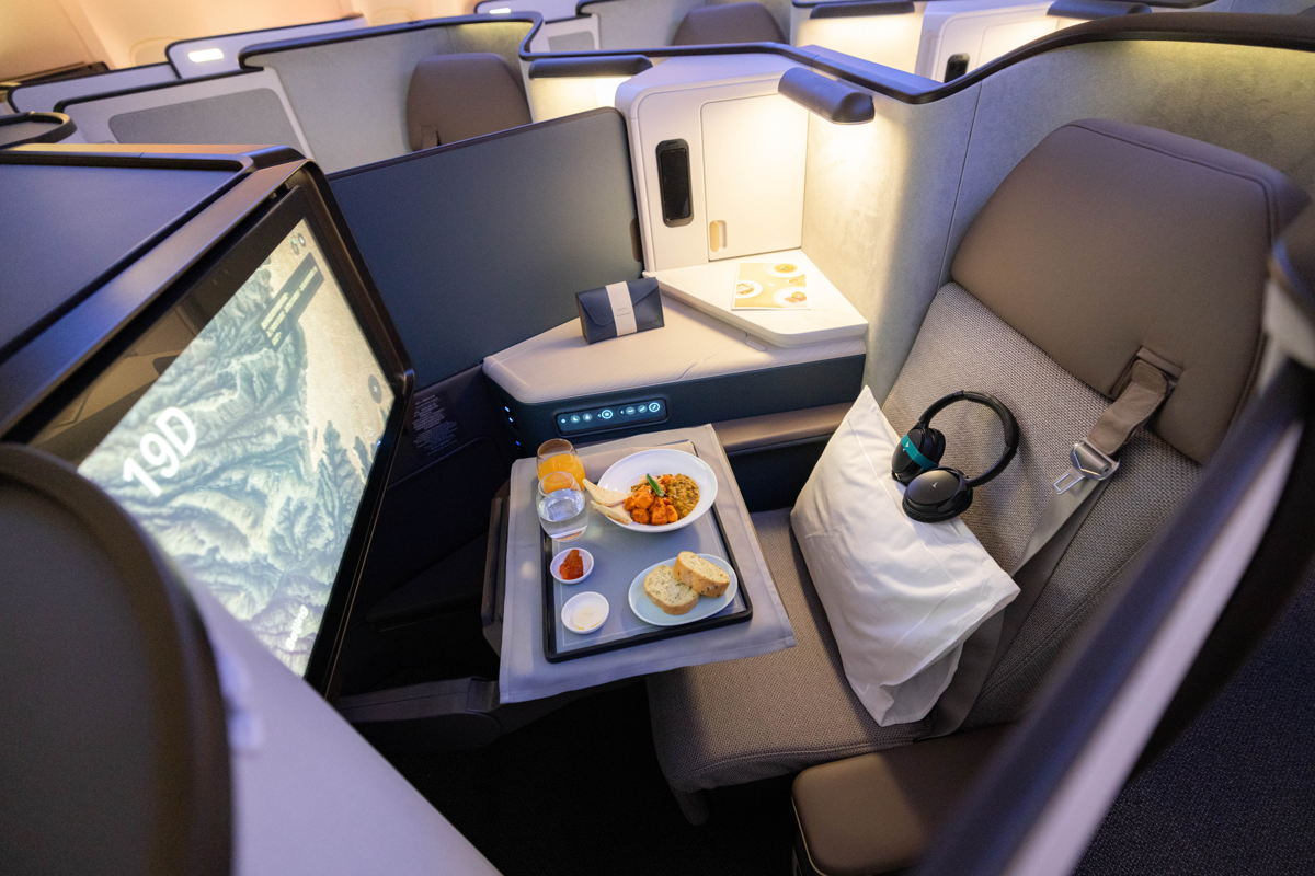 Ampia poltrona da aereo con tablet integrato, pasti gourmet, morbidi auricolari, e spazio personale per un viaggio in massimo comfort in Aria Suite di Cathay Pacific.
