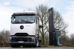 Veicolo elettrico Mercedes-Benz in ricarica presso stazione di ricarica pubblica, veicolo commerciale elettrico, sostenibilità e mobilità pulita, veicolo a zero emissioni, tecnologia innovativa.