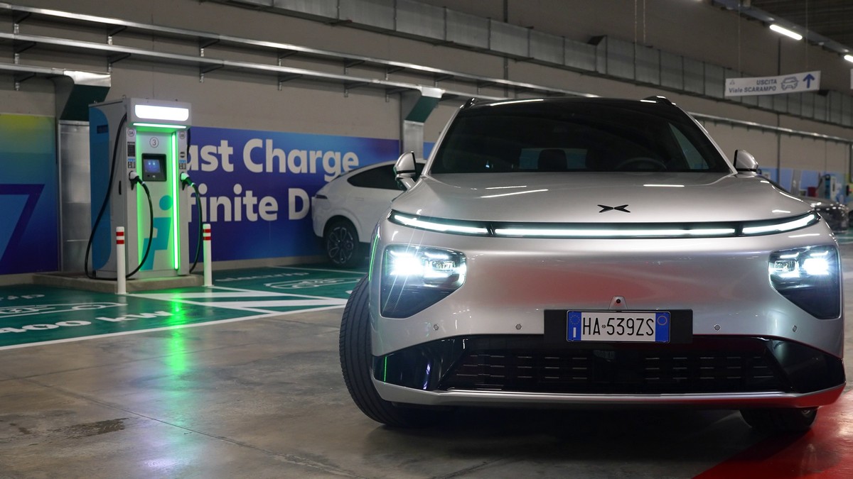 Altezza di una vettura elettrica futuristica in fase di ricarica, con stazione di ricarica rapida in garage coperto e illuminato, promuovendo mobilità sostenibile e tecnologia green.