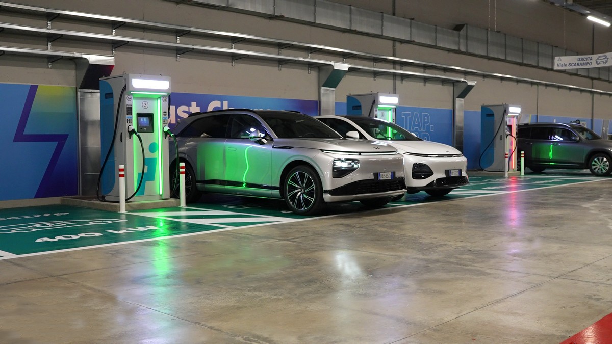 Stazione di ricarica per veicoli elettrici in un parcheggio coperto, con auto moderne che si ricaricano in spazi dedicati agli EV.
