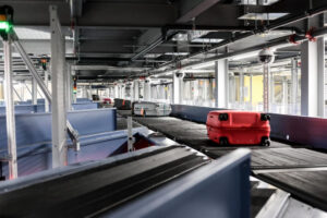 Bagagli in movimento sulla rampa di trasferimento, sistema di consegna aeroportuale, bagagli in viaggio verso volo, tecnologia di gestione bagagli, trasporto bagagli sicuro, logistics aeroportuale.